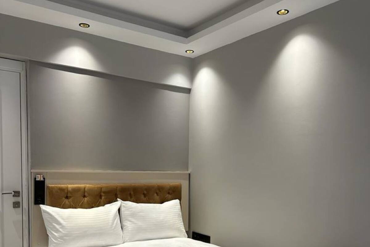 Une chambre moderne avec un lit, des murs gris et un éclairage encastré au plafond.