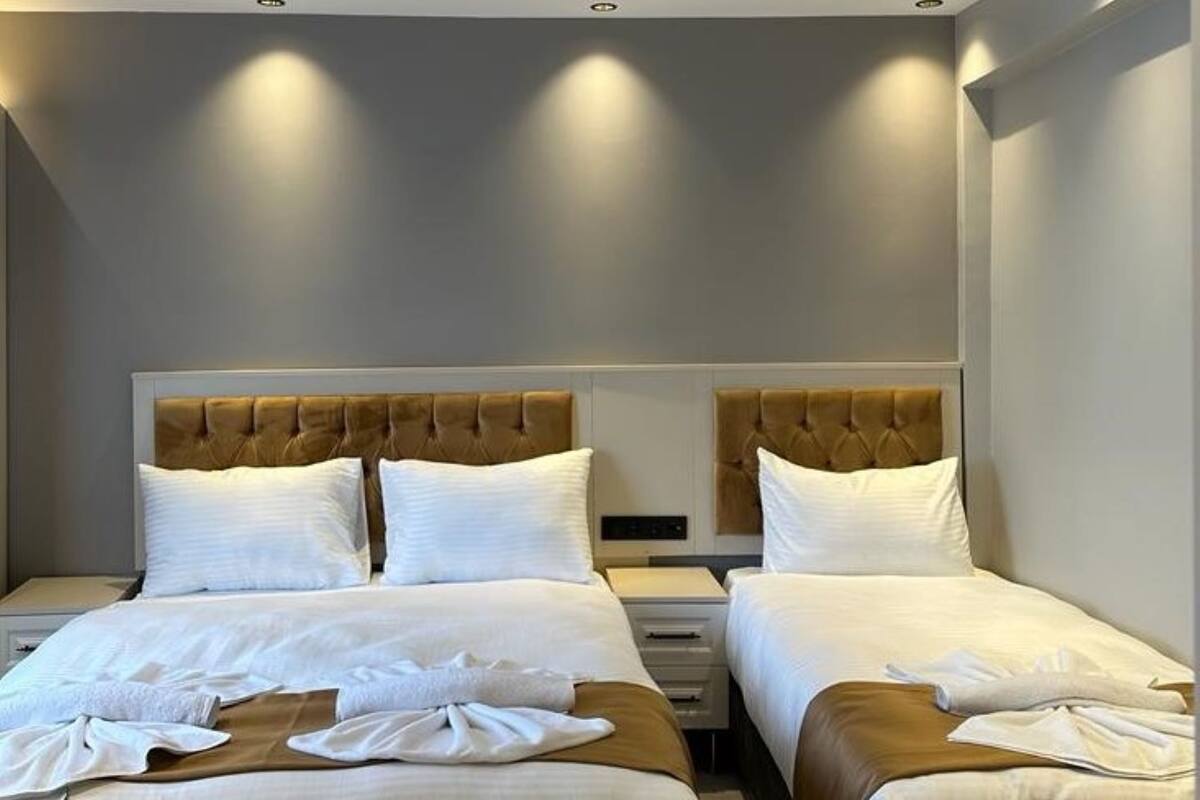 Une chambre d’hôtel avec deux lits, chacun doté d’une tête de lit, de draps blancs et d’une petite table de chevet.