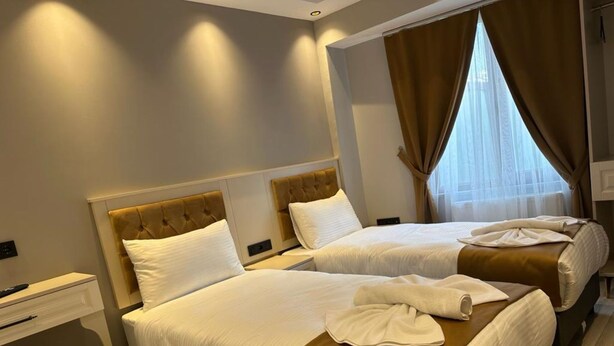 A hotel room with two beds, a desk, and a window with curtains. - Sareban Hotel Istanbul  (Istanbul)