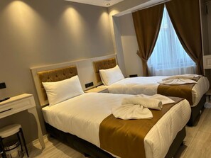 Une chambre d’hôtel avec deux lits, un bureau et une fenêtre avec des rideaux.