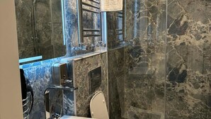 A bathroom with a marble wall, a sink, a toilet, and a shower enclosure. - Sareban Hotel Istanbul  (Istanbul)