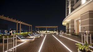 A rooftop lounge area with sun loungers, a pergola, and a view of the cityscape at night. - LYFE Hotels Bhubaneswar  (Bhubaneshwar)