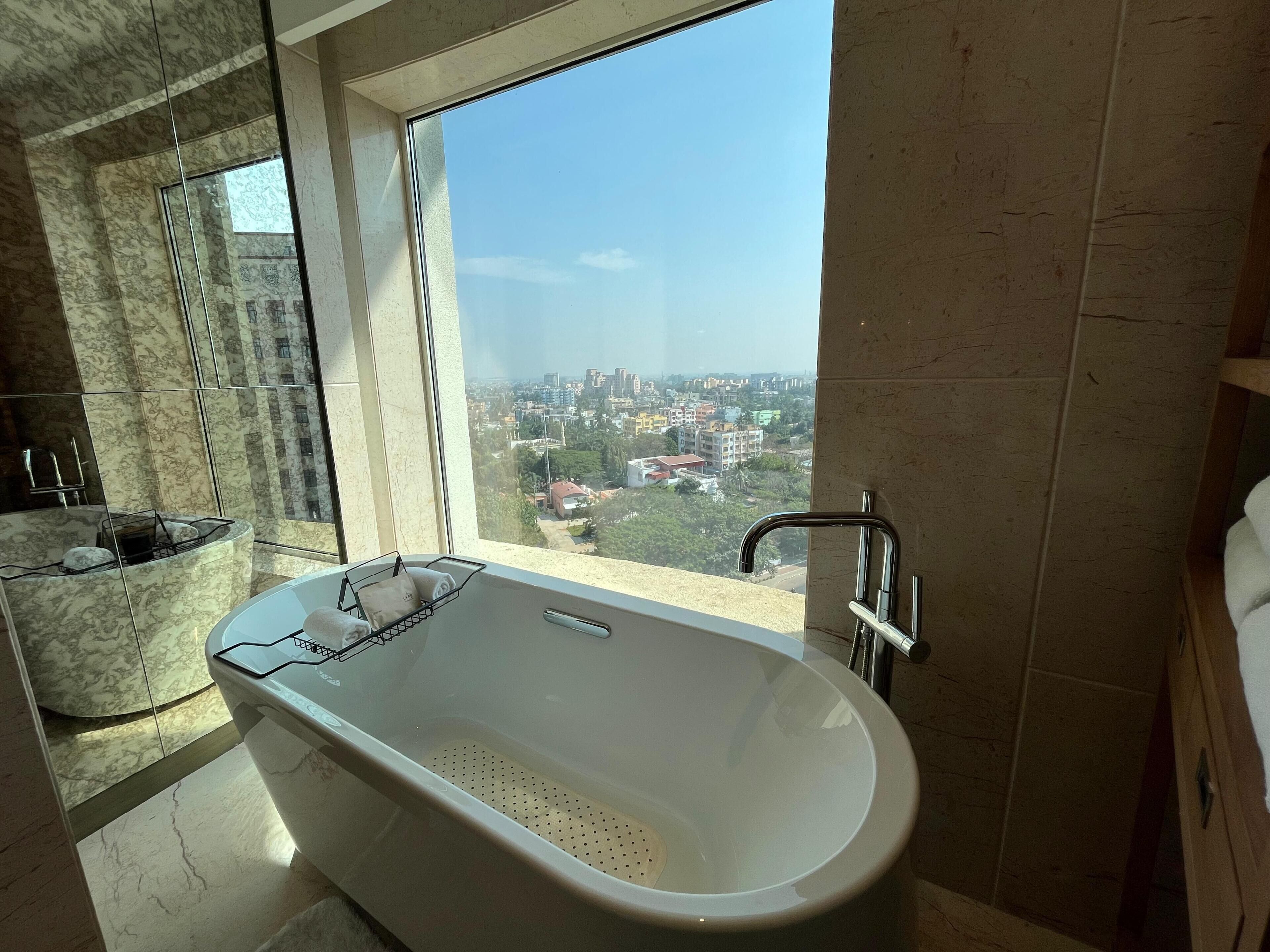 Un baño moderno con una bañera independiente, un ventanal grande y vista a la ciudad.