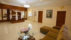 A spacious living area with a glass coffee table, a sofa, a wooden cabinet, and a canopy bed.