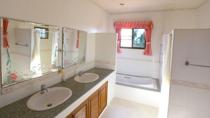 A bathroom with two sinks, a bathtub, and a window with a pink curtain.