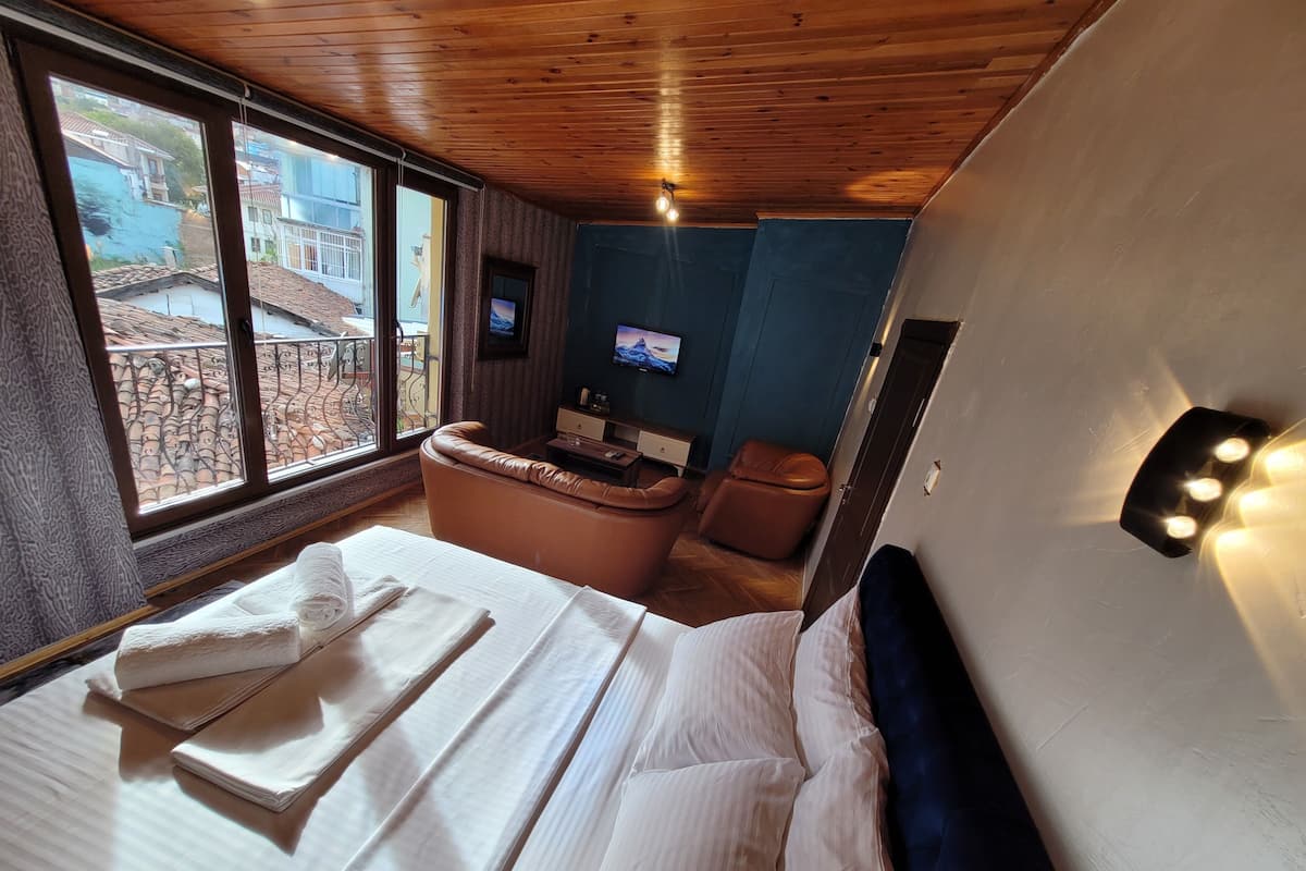 A hotel room with a large bed, a bathtub, a television, and a view of the outside.