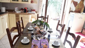 Une table à manger dressée avec des assiettes, des tasses et des plats, entourée de chaises en bois.