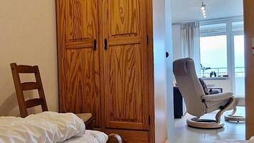 Ein Schlafzimmer mit zwei Betten, einem Holzschrank und einem Sessel.
