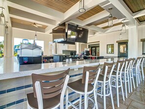 A modern kitchen with a large island, bar seating, and a flat-screen TV.