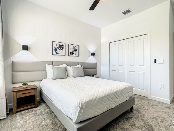 A bedroom with a bed, bedside tables, a wardrobe, and two wall-mounted lamps.