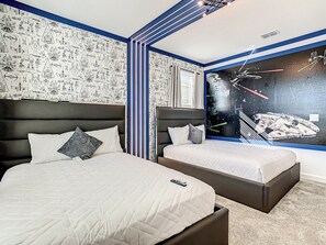 A bedroom with two beds, a large window with a space-themed mural, and patterned wallpaper.