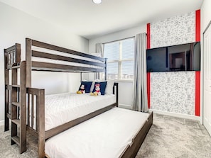 Una cama litera con almohadas, una ventana con cortinas y una pared con diseño.