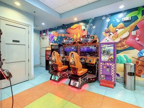 A room with arcade machines, a door labeled 'Employee Only,' and a mural on the wall.