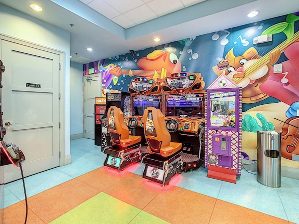 Una habitación con máquinas recreativas, una puerta con la leyenda 'Solo personal' y un mural en la pared.