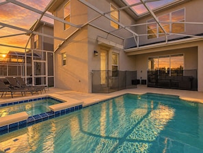 Una piscina interior con techo de vidrio, sillas de descanso y vistas de la puesta de sol.