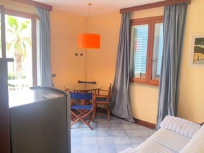 Ein Zimmer mit einem Bett, einem Tisch mit Stühlen, einem Fernseher und einem Fenster mit Vorhängen.