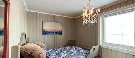Un dormitorio con cama, candelabro, ventana y un cuadro en la pared.