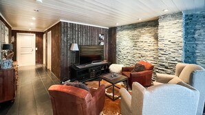 A modern living room with a stone wall, a fireplace, and comfortable seating.