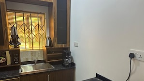 A compact kitchen with a Bosch microwave, a coffee maker, and a stove. - Kans Krib (Accra)