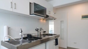 A modern kitchen with stainless steel appliances, white cabinetry, and a built-in dishwasher. - w* | Engaging 3BR with Balcony in Barranco (Barranco)