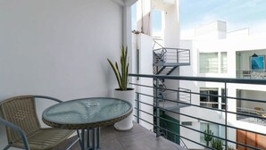 A balcony with a glass table and wicker chairs, a potted plant, and a metal railing. - w* | Engaging 3BR with Balcony in Barranco (Barranco)