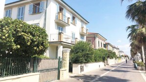 A street lined with multi-story buildings, some with balconies and shutters, and a clear sky above. - 5 Suite Grecale, primo piano, balcone di 25 mq lato interno, molto silenzioso (Cecina)