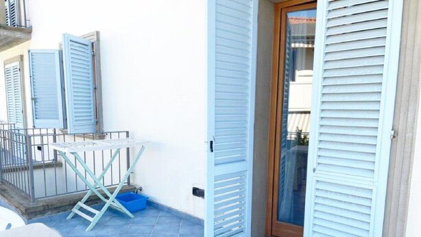 A balcony with a table and chairs, a drying rack, and a blue basin. - 5 Suite Grecale, primo piano, balcone di 25 mq lato interno, molto silenzioso (Cecina)
