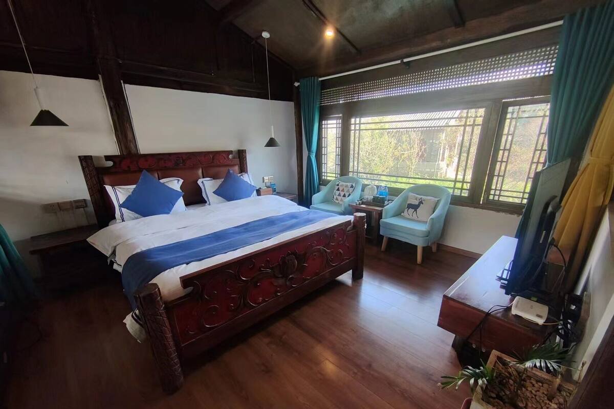Een slaapkamer met een groot bed, twee stoelen, een bureau en een televisie.