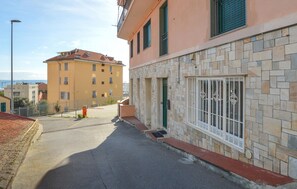 Eine enge Straße mit einem Gebäude, das eine Fassade aus Stein und einen Balkon hat.