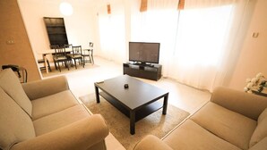 Ein Wohnzimmer mit zwei Sofas, einem Couchtisch, einem Fernseher und einem Essbereich mit Stühlen und Tisch.