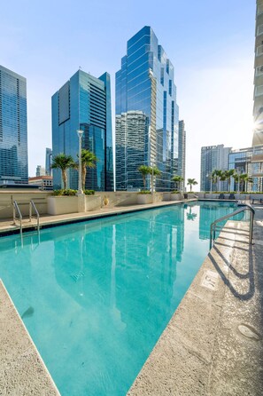 Une piscine offrant une vue sur les immeubles modernes qui s’élèvent en arrière-plan.