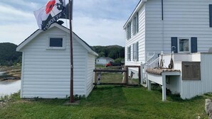 A white house with a porch and a flagpole with a flag.