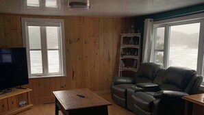 A living room with a wooden floor, a television, a sofa, a coffee table, and a bookshelf.