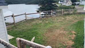 A view of a lake with a wooden fence and a white building in the background.