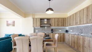 A modern kitchen with wooden cabinets, a granite countertop, and a dining area with beige chairs. - Karma House (Rethimno)
