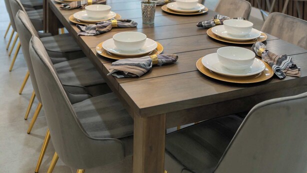 Un espace de restauration moderne avec une longue table en bois dressée pour un repas, entourée de chaises.