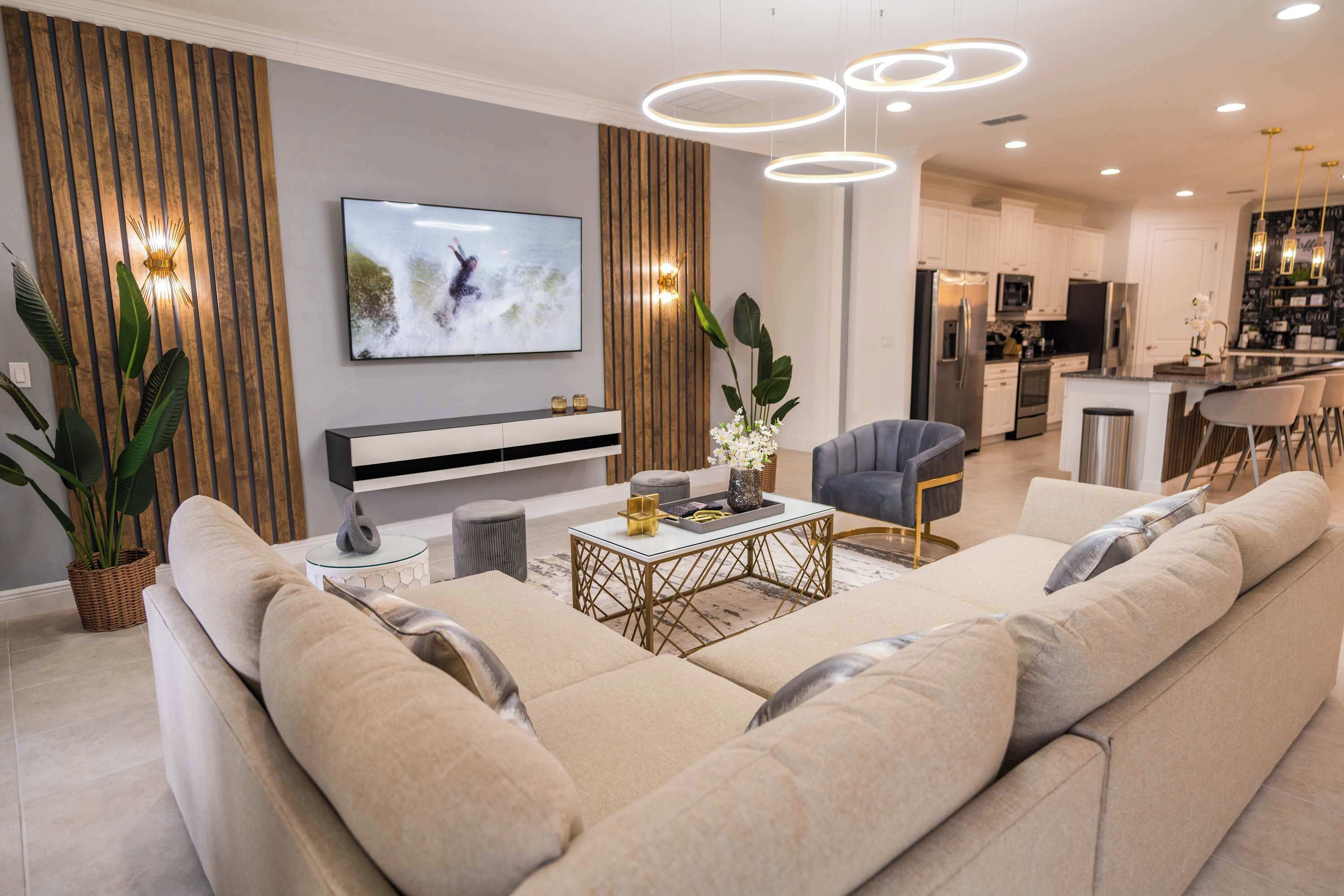 A modern living room with a large beige sofa, a coffee table, and a TV mounted on the wall.