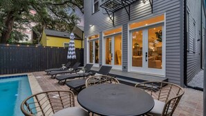 A backyard with a swimming pool, lounge chairs, and a table. - New Home Great for Groups | Heated Pool, Sleeps 10 (New Orleans)