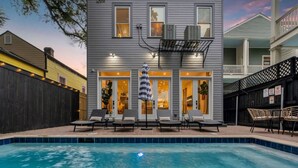 A two-story house with a swimming pool, outdoor seating, and a covered patio area. - New Home Great for Groups | Heated Pool, Sleeps 10 (New Orleans)