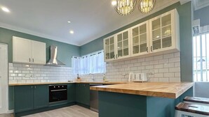 A modern kitchen with teal cabinetry, white countertops, and a central island. - SandyBay Garden Hideaway (Sandy Bay)