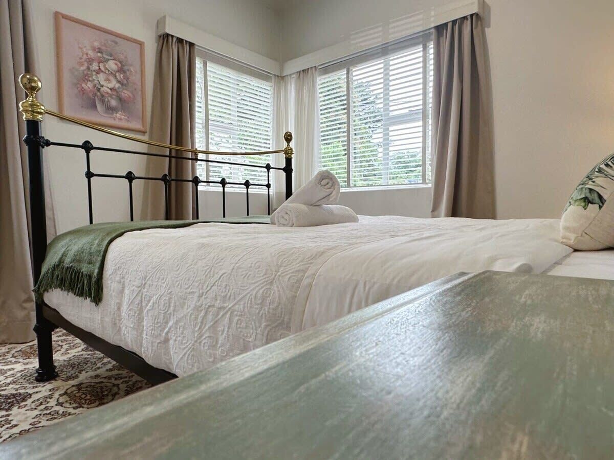 A bedroom with a bed, a window with curtains, and a painting on the wall.