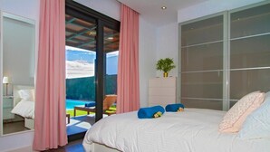 A bedroom with a large bed, a sliding glass door to a balcony, and a view of a pool. - Villa Zanata with air conditioning and hot tub (Puerto del Carmen)