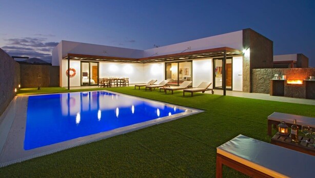 A modern house with a swimming pool, outdoor seating, and a stone fireplace. - Villa Zanata with air conditioning and hot tub (Puerto del Carmen)