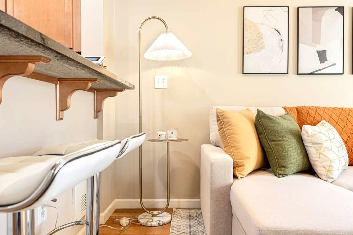 Een moderne woonkamer met een witte bank, een vloerlamp en abstracte kunst aan de muur.