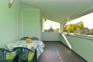 Enjoy a balcony with a table for two, overlooking a tranquil residential area with lush trees.