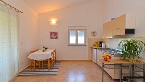 A compact kitchen with a dining area, a small refrigerator, and a window with blinds. - Holiday apartment with air conditioning (Banjole)