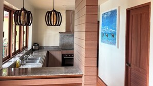 A modern kitchen with a central island, pendant lights, and a wooden column. - The great escape private sea-view pool villa, 5 min from the beach (Koh Lanta)