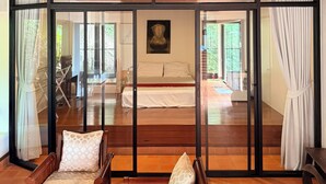 A room with a bed, two chairs, a wooden ceiling, and large glass doors leading to another room. - Private Pool Villa · Kantiang Bay Sea Views · Koh Lanta (Koh Lanta)