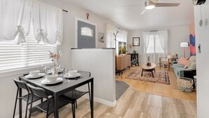 A modern living room with a dining area, a ceiling fan, and a door with a window. - Lil' Love Shack ~ Private Yard (Loveland)