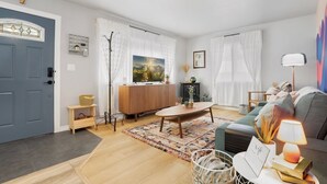 A modern living room with a blue door, a wooden coffee table, a grey sofa, and a lamp. - Lil' Love Shack ~ Private Yard (Loveland)